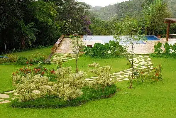 Área externa da casa de chácara com jardim e piscina.