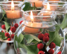 Imagem de arranjos de natal em vasos de vidro, com flores e água, trazendo um clima festivo.